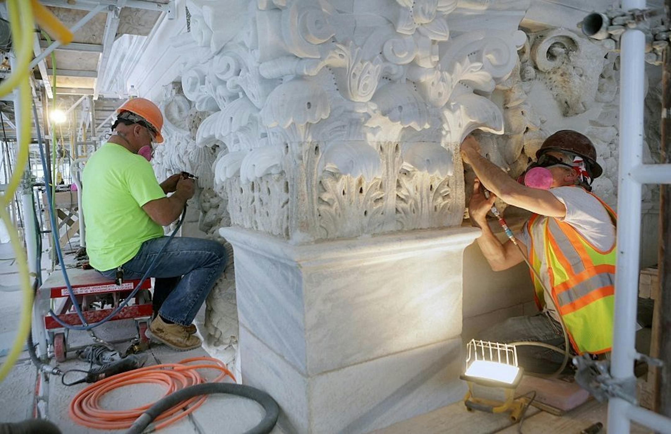 In this photo taken March 9, 2015, stonecarvers work on exterior details of the Minnesota Capitol in St. Paul, Minn. A major renovation of the state Capitol is threatening to run $30 million over budget, state officials advised lawmakers Friday, March 27, 2015.