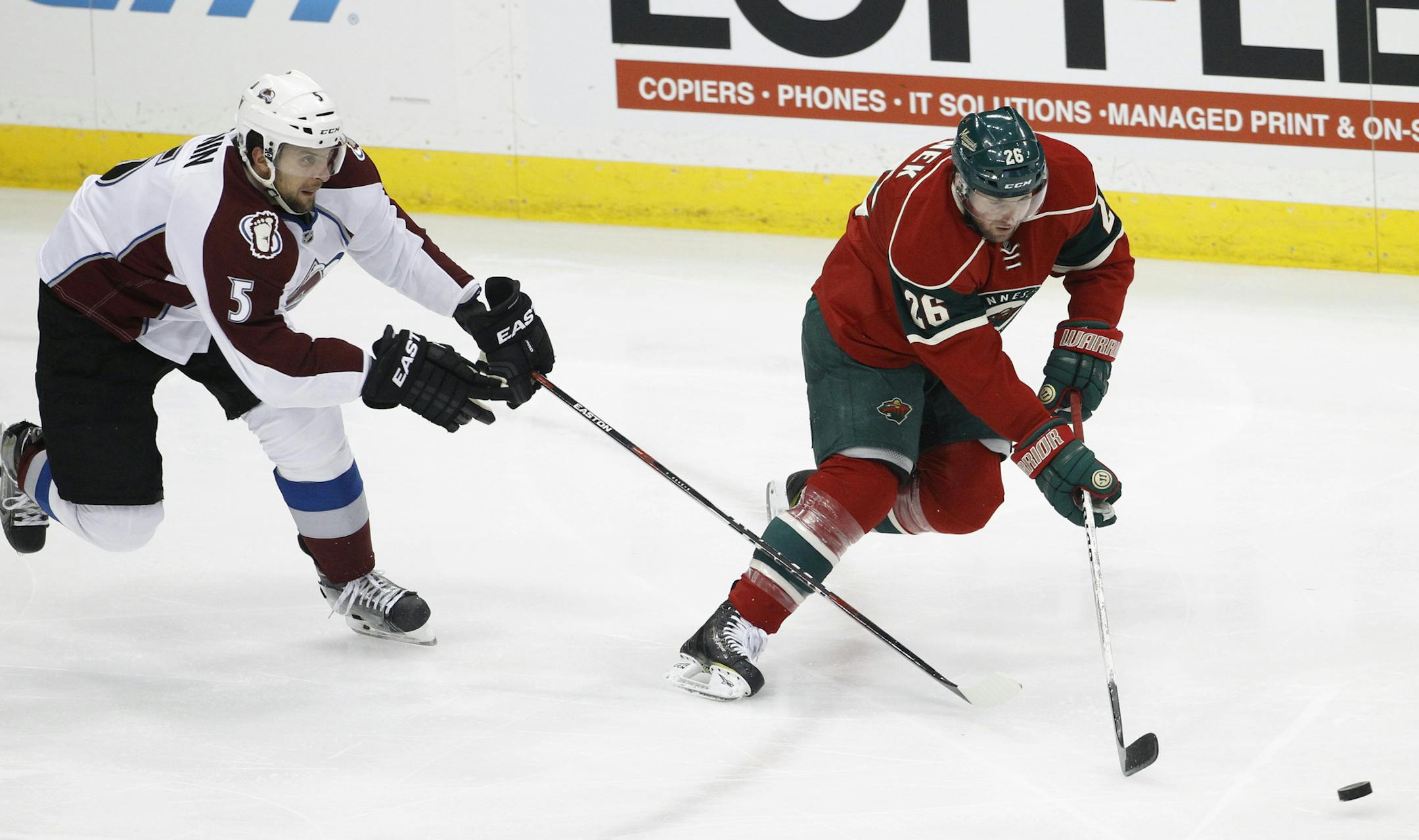 Minnesota Wild left wing Thomas Vanek (26), of Austria, and Colorado Avalanche defenseman Nate Guenin (5) chase the puck during the first period of an NHL hockey game in St. Paul, Minn., Saturday, Feb. 7, 2015. (AP Photo/Ann Heisenfelt)