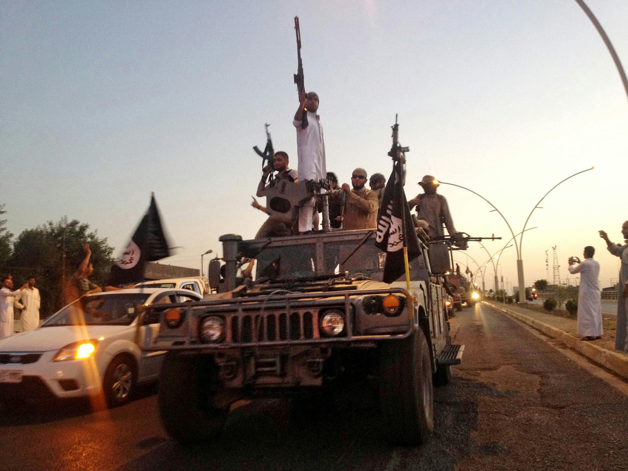FILE - In this file photo taken Monday, June 23, 2014, fighters from the Islamic State group parade in a commandeered Iraqi security forces armored vehicle down a main road at the northern city of Mosul, Iraq. (AP Photo, File) ORG XMIT: MIN2014091711132620