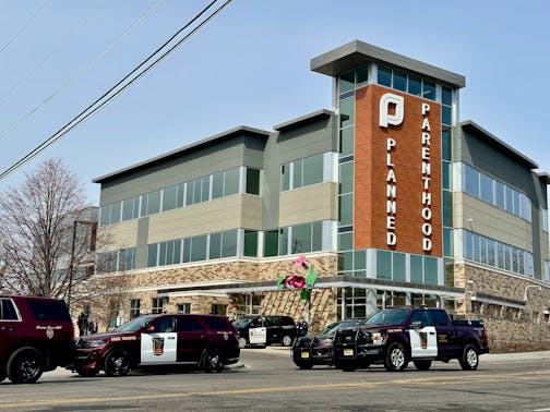 three police cruisers sit in the street in front of a building that has a sign saying planned parenthood