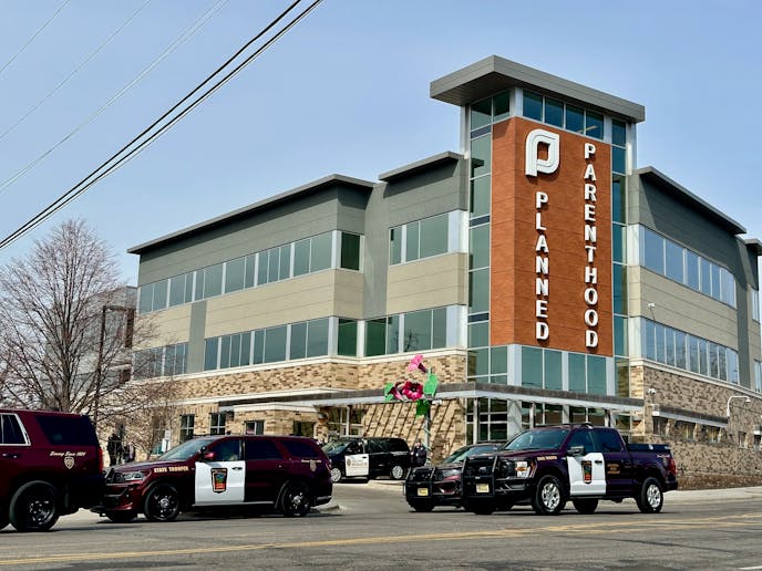 three police cruisers sit in the street in front of a building that has a sign saying planned parenthood
