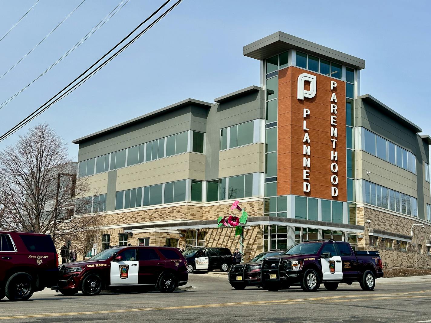 three police cruisers sit in the street in front of a building that has a sign saying planned parenthood