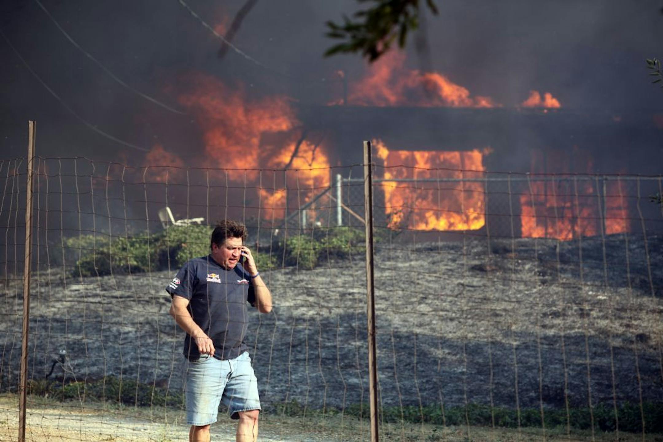Dave Clark, of Twin Pines, tells a neighbor their house is ok as his own house burns on Wednesday, Aug. 7, 2013.