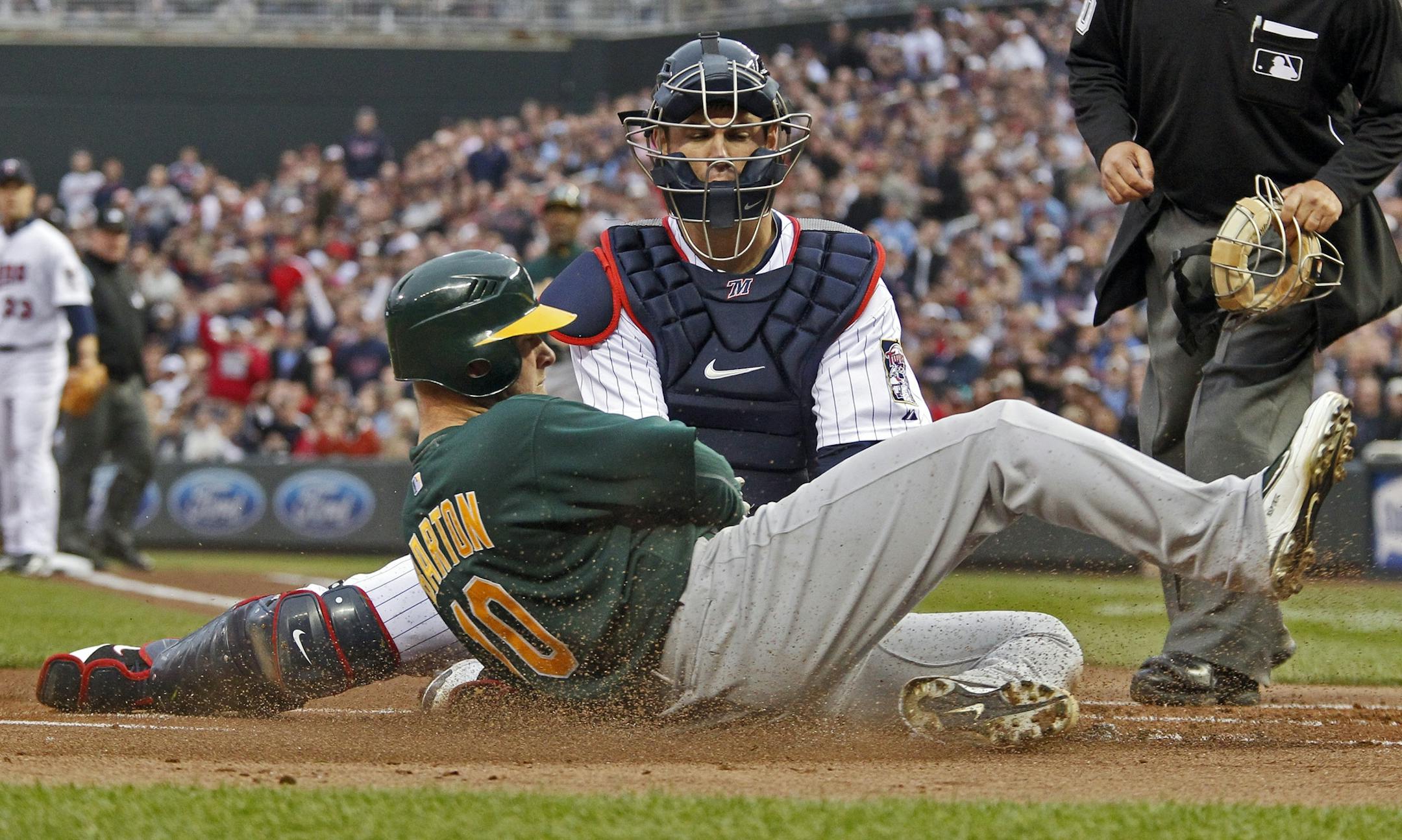 Twins catcher Joe Mauer tagged out Oakland runner Daric Barton as he slid into home.