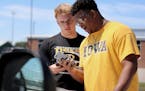 Hutchinson football players Ty Glaser, left, and Jordan Titus monitor their phones while waiting to hear how the MSHSL would vote on the upcoming foot