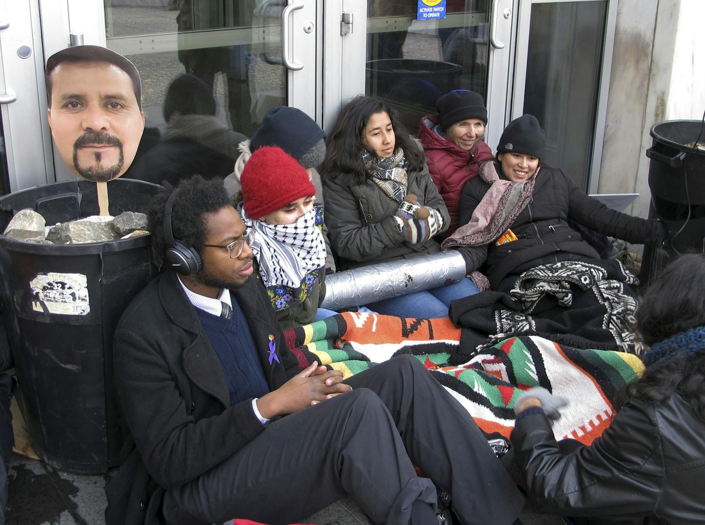 FILE - In this Nov. 30, 2018 file photo, supporters of Nelson Pinos, an immigrant from Ecuador who has been living in a church for a year to avoid deportation, block the front doors outside the federal building, in Hartford, Conn. An attorney for Pinos, who was arrested in Minneapolis and ordered deported from the U.S. 25 years ago, goes to court Tuesday, May 13, 2019, to ask that his case be reopened. (AP Photo/Dave Collins, File)