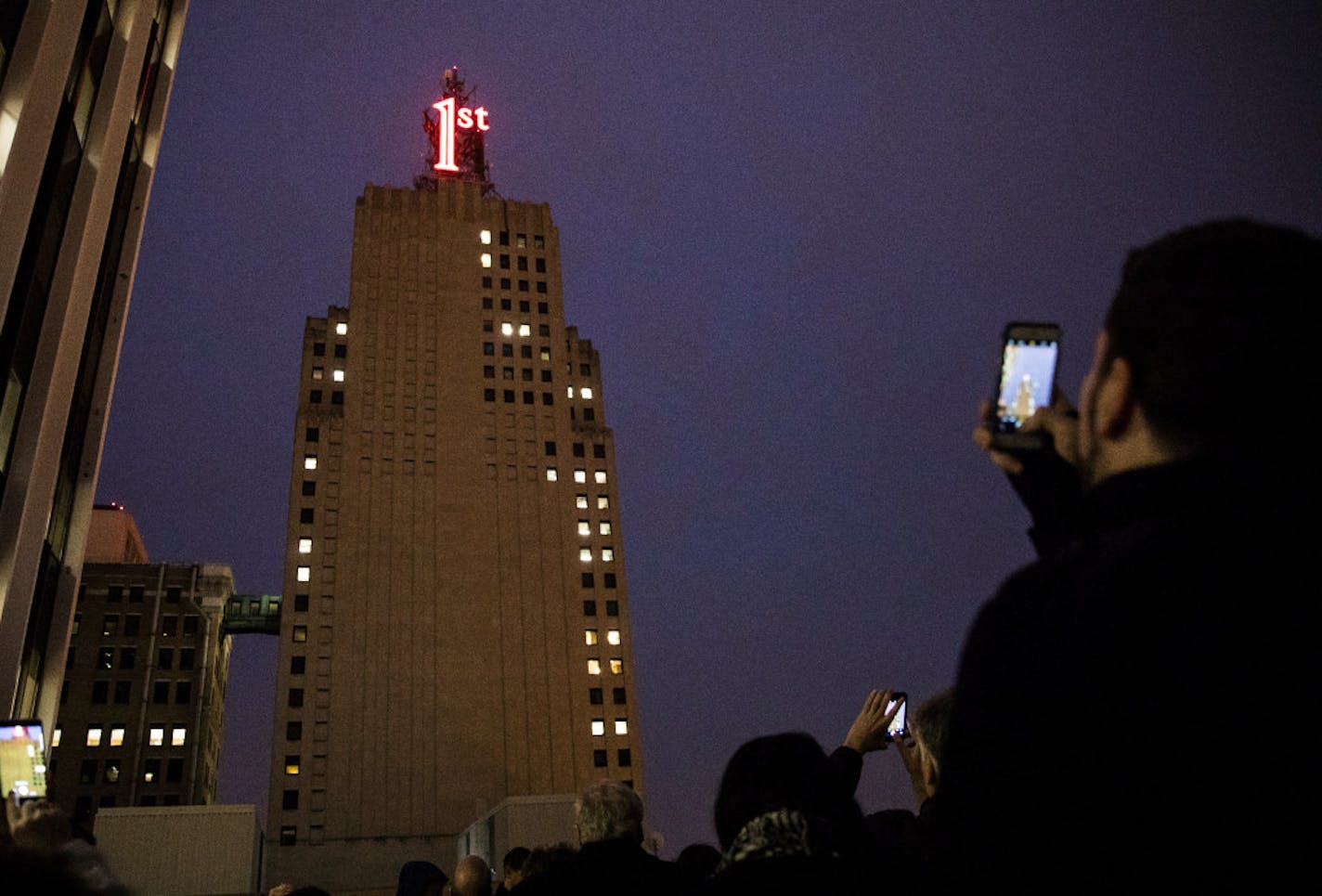 A crowd at the neighboring U.S. Bank building photographed the re-lighting of the iconic red First National Bank Building sign in 2016. The two buildings will not be included in a St. Paul improvement district.