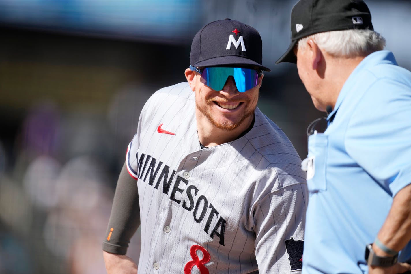 Minnesota Twins first baseman Christian Vazquez jokes with first base umpire Larry Vanover in the sixth inning of a baseball game against the Colorado Rockies, Sunday, Oct. 1, 2023, in Denver. (AP Photo/David Zalubowski)