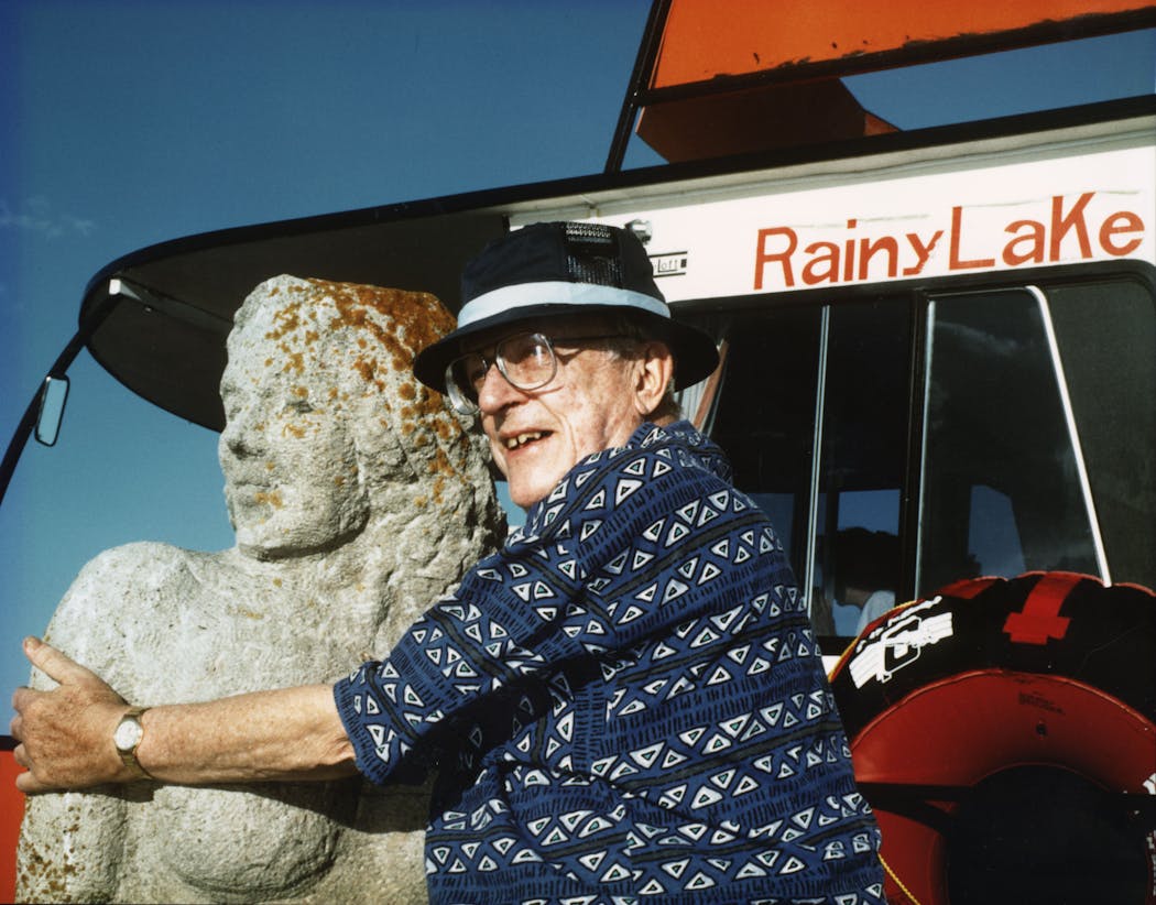 Gordon Schlichting, architect and artist, with his sculpture of a mermaid on the shore of Rainy Lake.