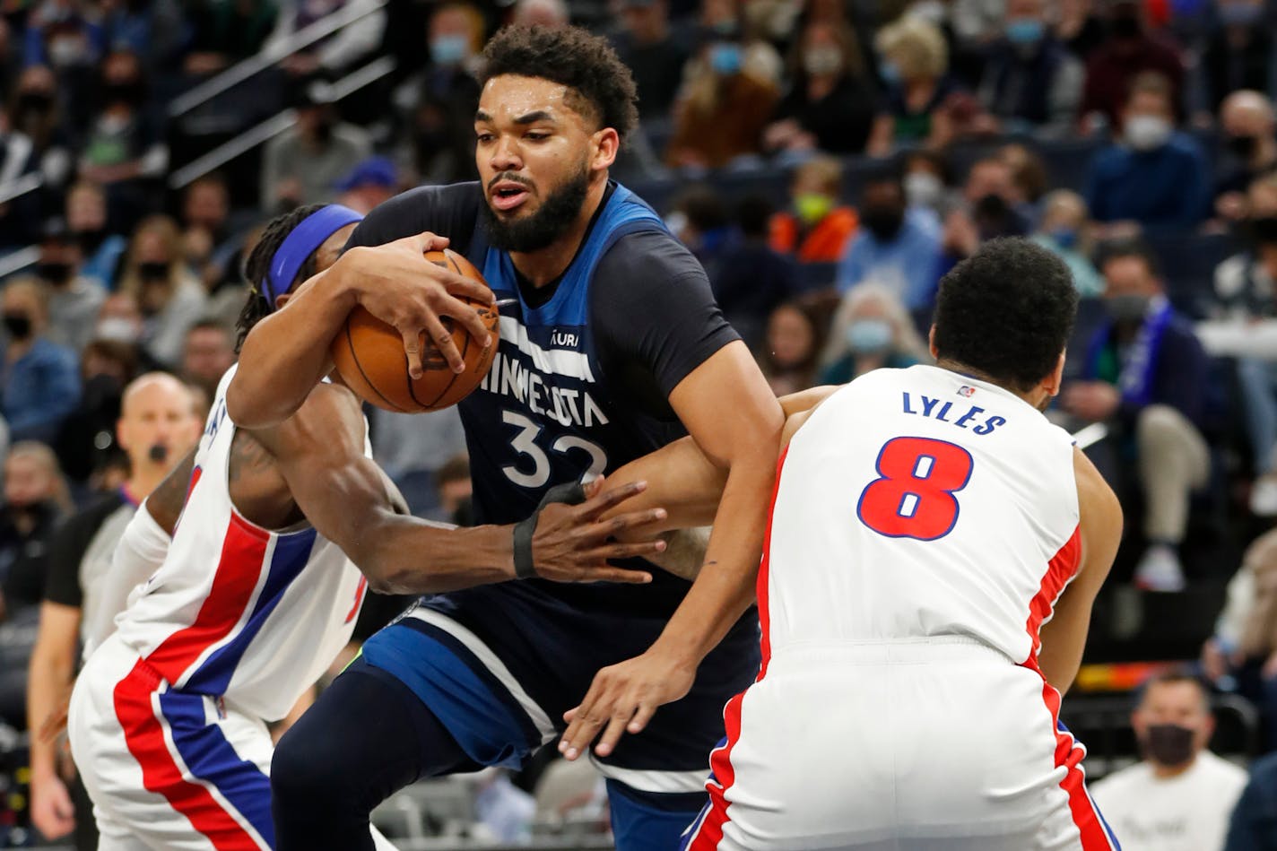 Minnesota Timberwolves center Karl-Anthony Towns (32) works between Detroit Pistons forward Jerami Grant, left, and Detroit Pistons center Trey Lyles, right, in the first quarter of an NBA basketball game, Sunday, Feb. 6, 2022, in Minneapolis. (AP Photo/Bruce Kluckhohn)