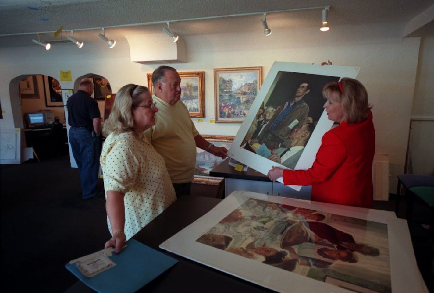 St. Louis Park, Mn Elayne's Gallery 7/11/01----Bonnie Lindberg right show Jim and Joyce Vaughan of Northfield a Norm Rockwell print at Elayne's Gallery in St. Louis Park. Bonnie's mother Elayne Lindberg owned the gallery before her daughter, and the Vaughan's bought another Rockwell painting called "Looking out to sea" 25 years ago from Elayne.