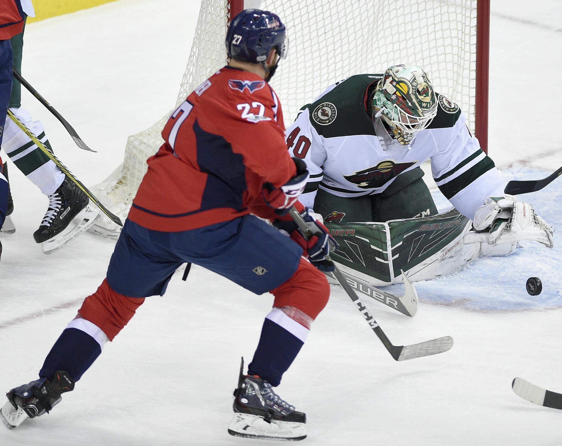 Minnesota Wild goalie Devan Dubnyk (40) reaches for the puck against Washington Capitals defenseman Karl Alzner (27) during the third period of an NHL hockey game, Tuesday, March 14, 2017, in Washington. The Capitals won 4-2. (AP Photo/Nick Wass)