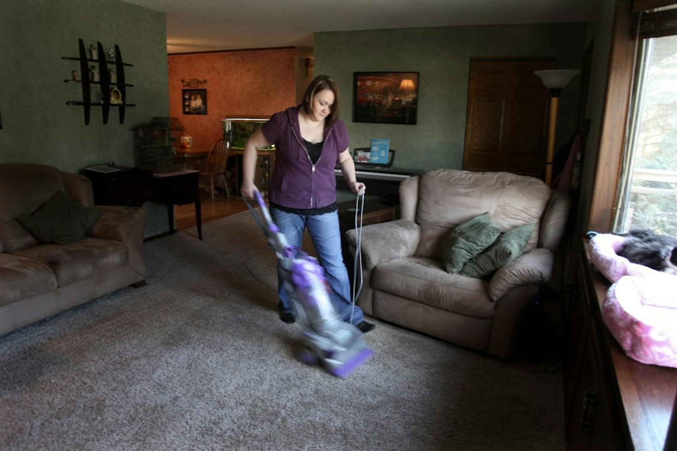 Laura Nielsen vacuumed her living room Tuesday, November 15, 2011. The second annual Working Mother study released last month revealed that both working and stay-at-home moms feel guilty about how much time they spend with family, contributing to the family income and not using their college education.