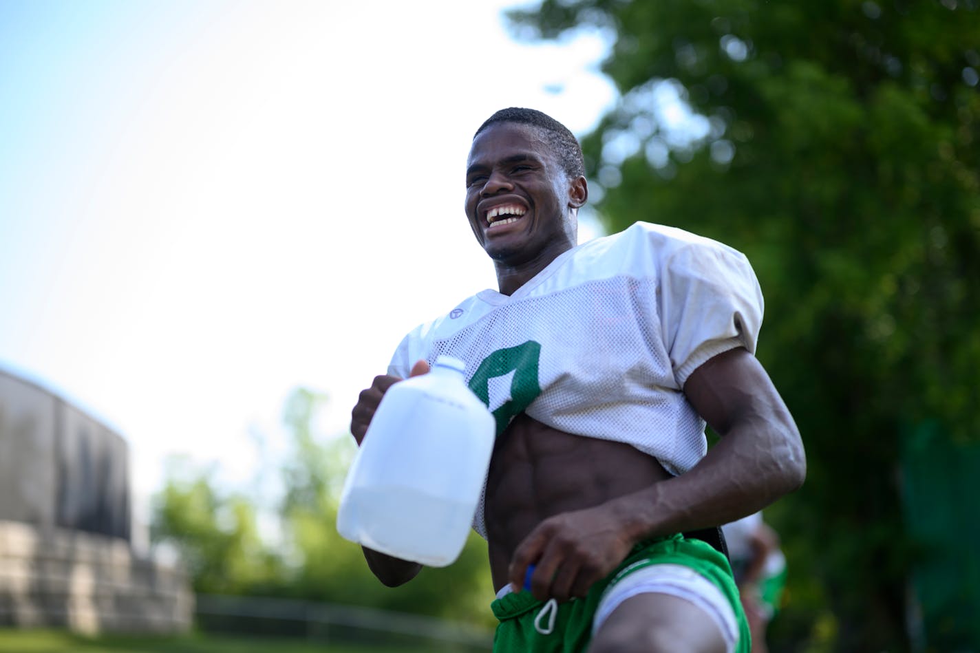 Running back Sawyer Seidl laughs with teammates during a hydration break Tuesday, Aug. 23, 2022 at Hill-Murray High School in Maplewood, Minn.. Seidl is emerging as one of the top players in the metro, despite playing at a school not known for football success. He and younger brother Simon were adopted from an orphanage in Congo. ] aaron.lavinsky@startribune.com