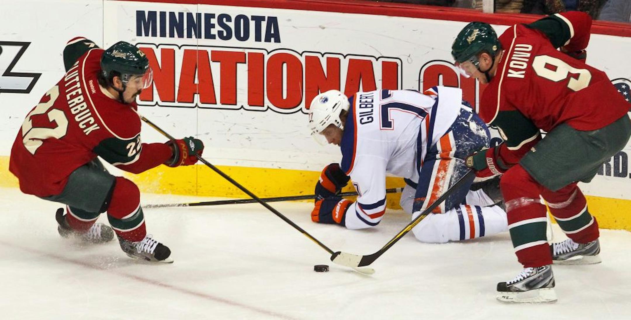 The Minnesota Wild's Cal Clutterbuck (22) and Mikko Koivu (9) keep the puck from the Edmonton Oilers' Tom Gilbert at the Xcel Center in St. Paul, Minnesota, on Thursday, December 29, 2011.