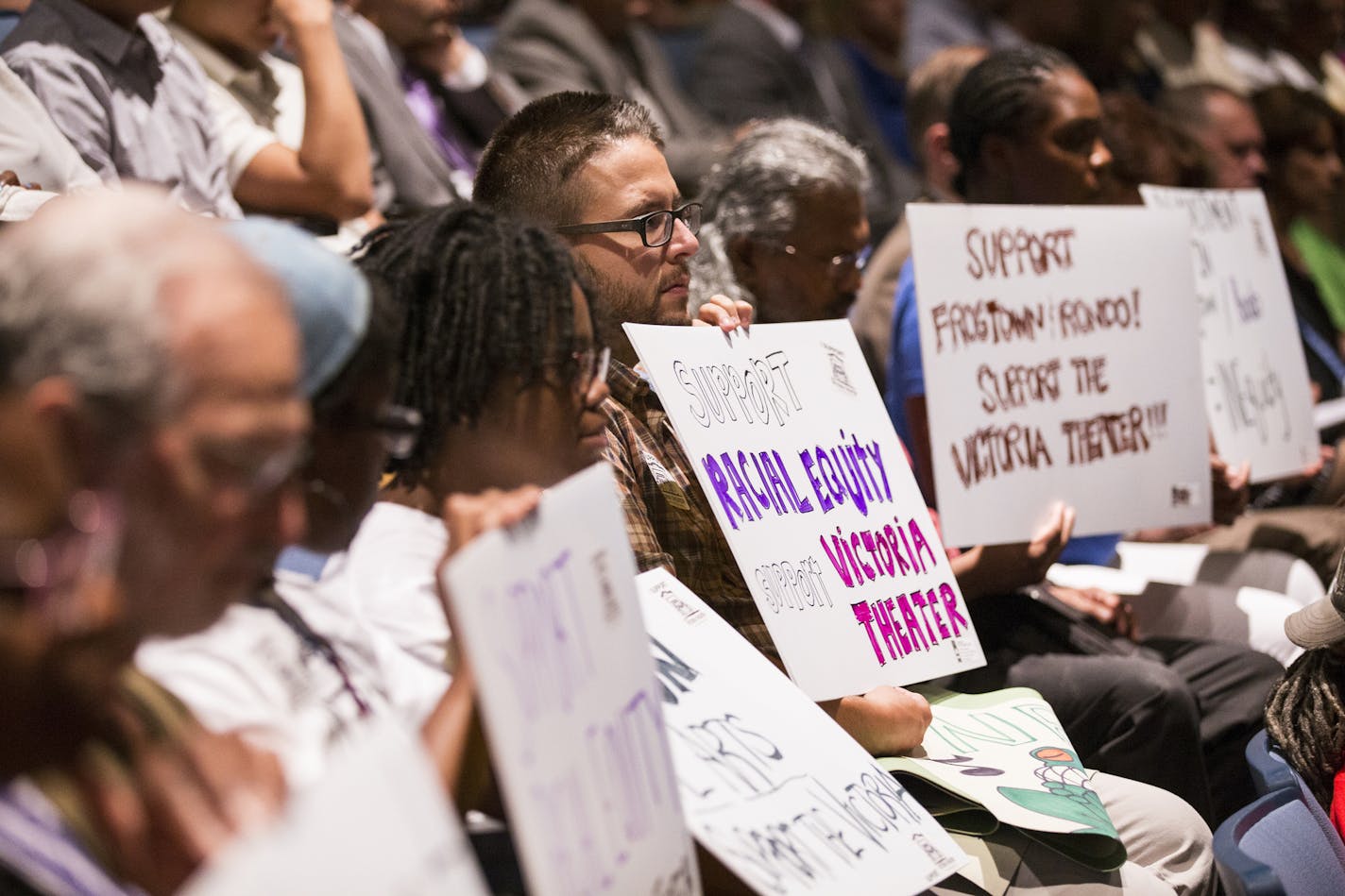 People hold signs in support of the Frogtown and Rondo neighborhoods as St. Paul Mayor Chris Coleman delivers his 2016 budget address to the City Council at the the Wellstone Center in St. Paul on Tuesday.