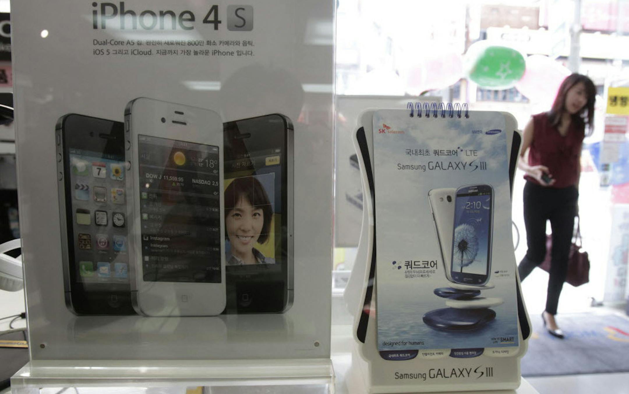 Banners advertising Samsung Electronics' Galaxy S III and Apple's iPhone 4S are displayed at a mobilephone shop in Seoul, South Korea.
