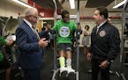 Gov. Tim Walz, left, and actor and fitness trainer Jake Steinfeld chatted with student Yusuf Ali as he tried out E-STEM Middle School's new fitness ce