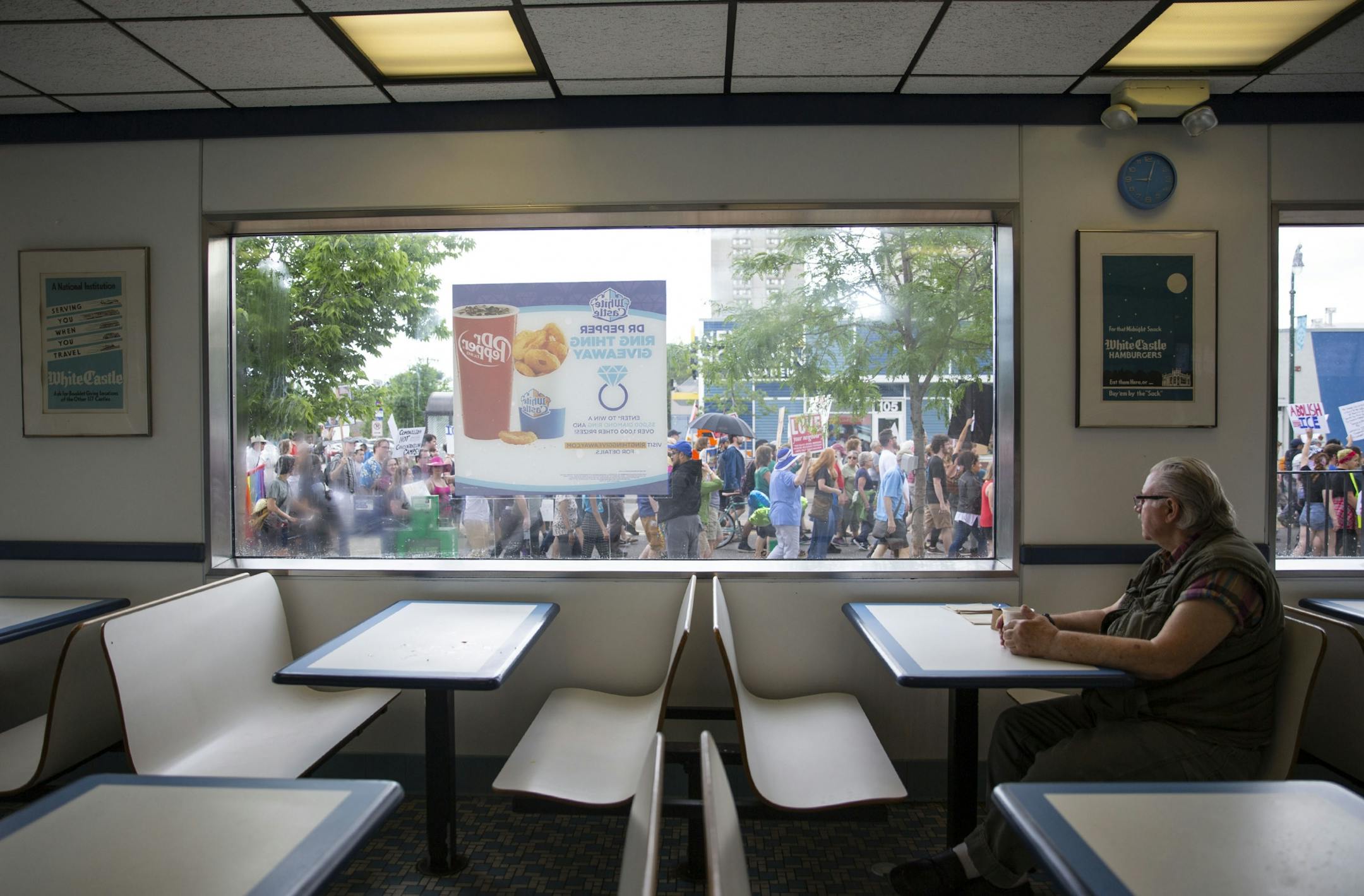 Joe Svoboda looks outside the window of a White Castle at the march of protestors down Lake Street. ALEX KORMANN ¥ alex.kormann@startribune.com Approximately 1,000 people marched through the streets of Minneapolis on Sunday June 30, 2019 protesting the treatment of migrants on the U.S. border. "Stop separating families, close the camps," said Mari Mansfield, an organizer for the event.