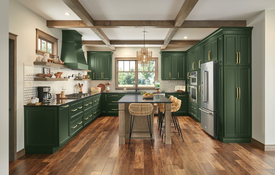 Green cabinets, gold hardware and textured seating help give this kitchen a cozy feel.