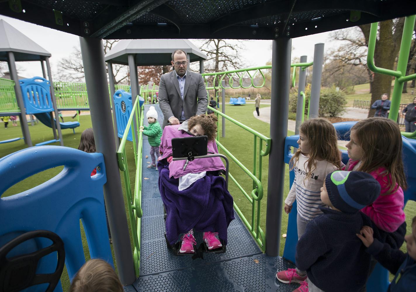 Mike Garvin leads his daughter Ashley, 13, who has cerebral palsy, through the new playground structure which is handicap accessible, at Rosland Park in Edina. ] (Leila Navidi/Star Tribune) leila.navidi@startribune.com BACKGROUND INFORMATION: A ribbon cutting ceremony and grand opening of a universal playground at Rosland Park in Edina on Wednesday, October 26, 2016. A universal playground is opening in Edina, part of a recent trend by parents who want more accessible public equipment for childr