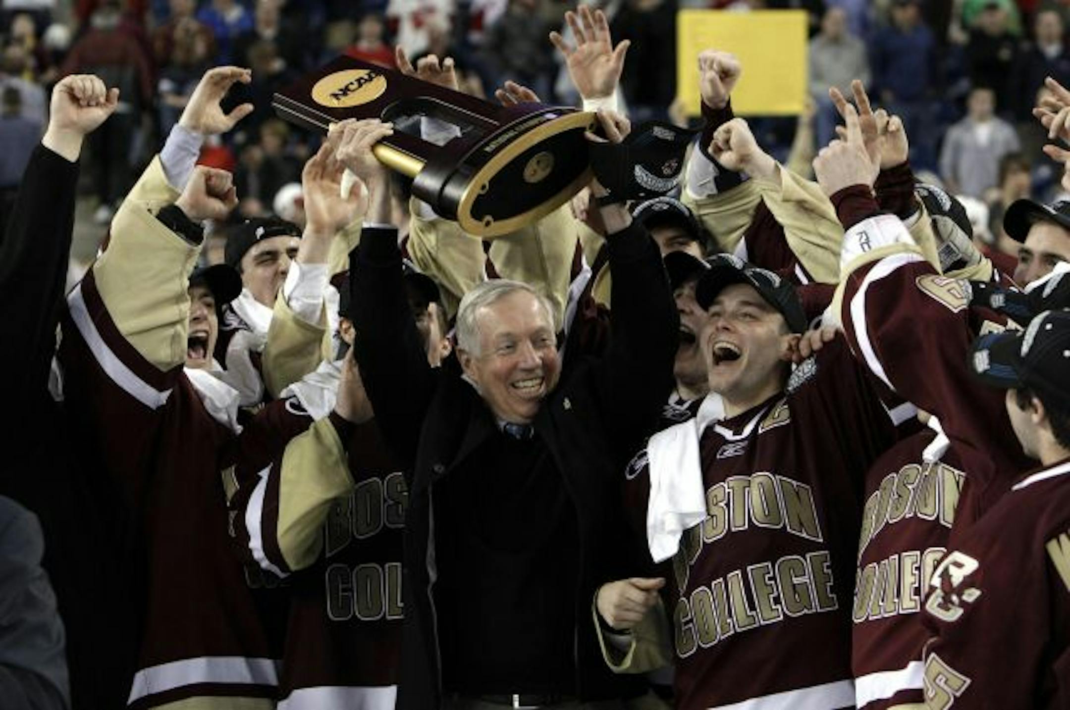 Boston College head coach Jerry York, center, holds up the championship trophy while celebrating their 5-0 victory over Wisconsin in the NCAA Frozen Four championship hockey game in Detroit, Saturday, April 10, 2010.