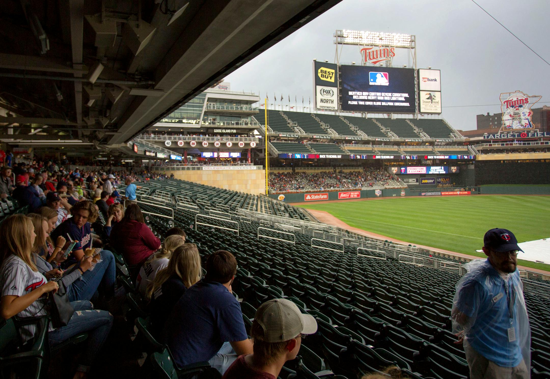 Fans seek shelter during a rain delay before a baseball game between the Minnesota Twins and the Texas Rangers on Saturday, Aug. 5, 2017 in Minneapolis. (AP Photo/Andy Clayton-King)