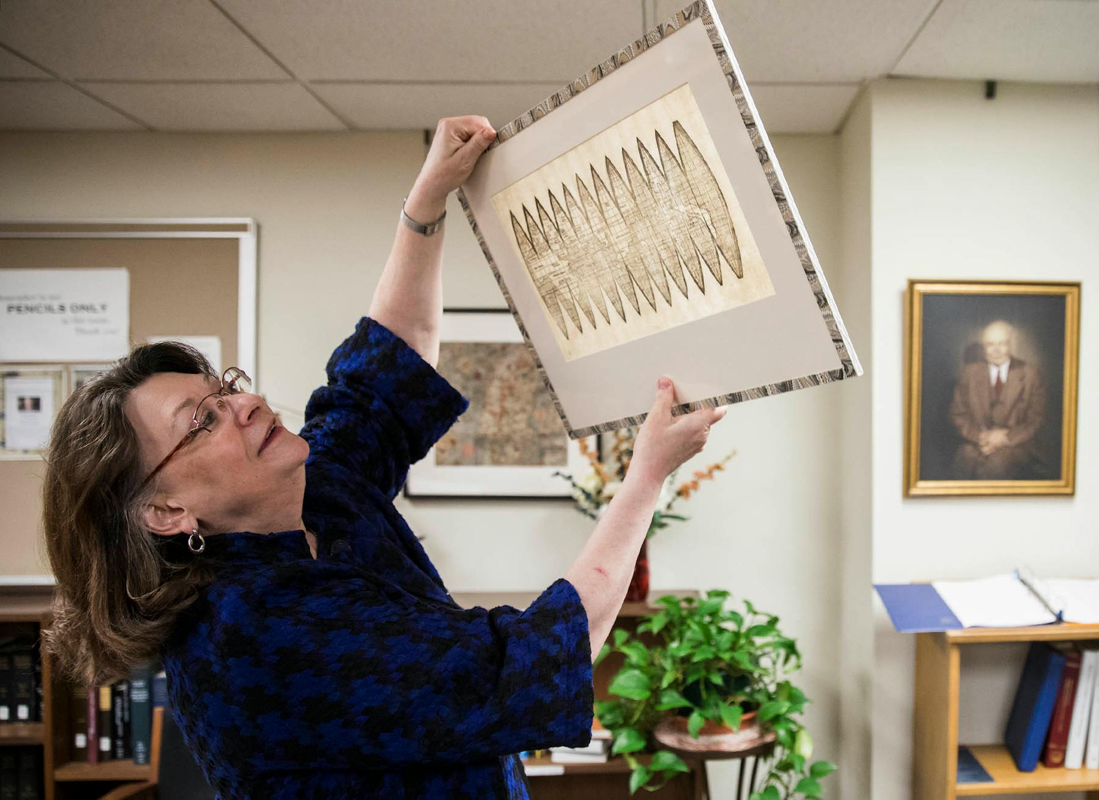 Marguerite Ragnow, curator of the James Ford Bell Library, holds the globe gores map up to the light to show some of it's distinctive characteristics.