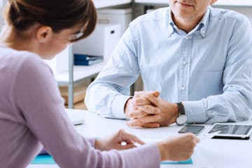 Mature businessman and young woman having a business meeting in the office, they are discussing together