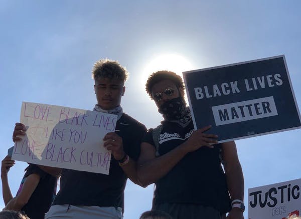 Gophers football players Brevyn Spann-Ford (left) and Seth Green held signs at the protest on the I-35W bridge Sunday in Minneapolis.