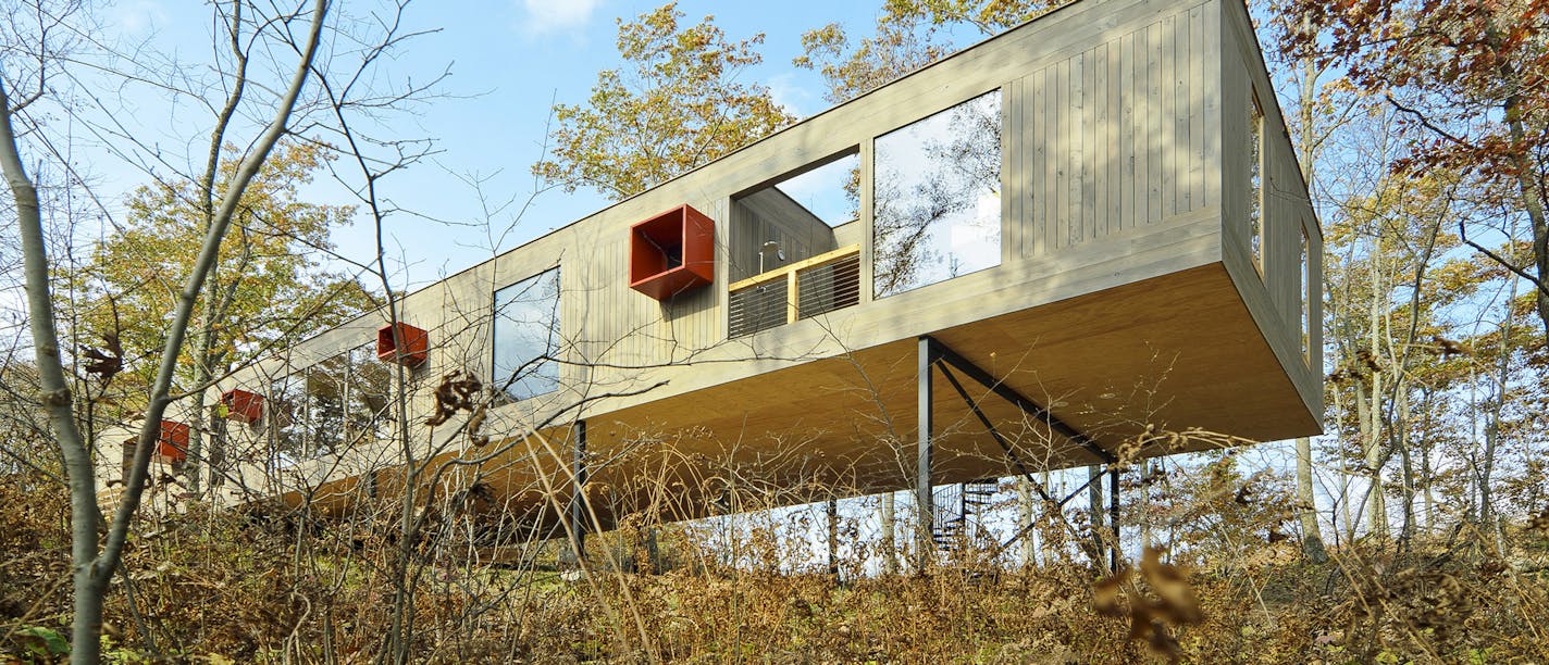 The Lazor-designed Peek-a-Boo, located in New Auburn, Wis., is elevated on legs and engulfed in a canopy of trees.