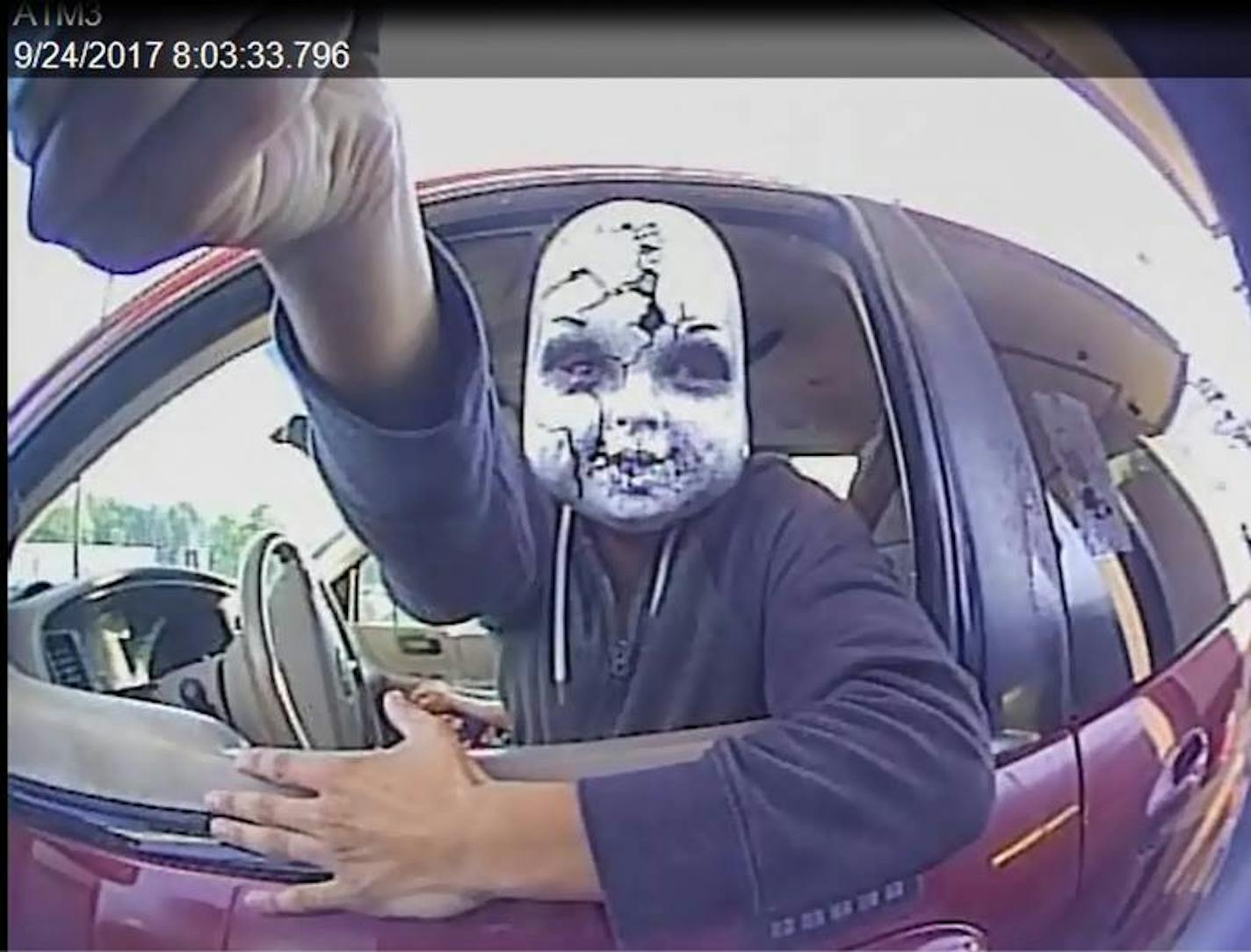 A suspect believed to have placed skimmers at outdoor ATM machines dons a skull-type mask to conceal his identity