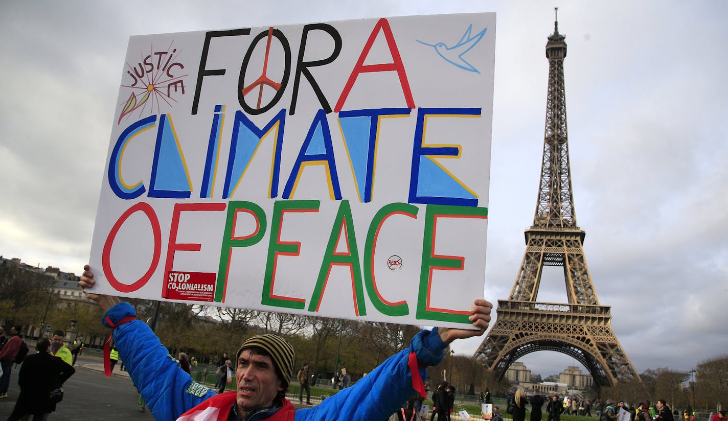 An activist hold a poster during a demonstration near the Eiffel Tower, in Paris, Saturday, Dec.12, 2015 during the COP21, the United Nations Climate Change Conference. As organizers of the Paris climate talks presented what they hope is a final draft of the accord, protesters from environmental and human rights groups gather to call attention to populations threatened by rising seas and increasing droughts and floods. (AP Photo/Thibault Camus) ORG XMIT: MIN2015121414182228