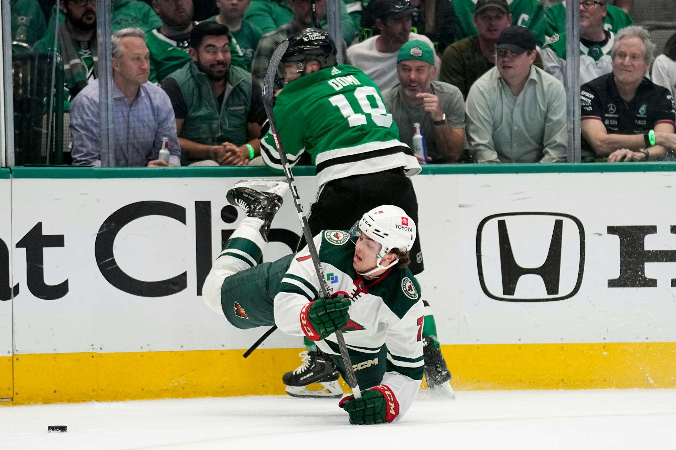 Minnesota Wild defenseman Brock Faber (7) falls to the ice as he and Dallas Stars' Max Domi (18) compete for control of the puck in the first period of Game 2.