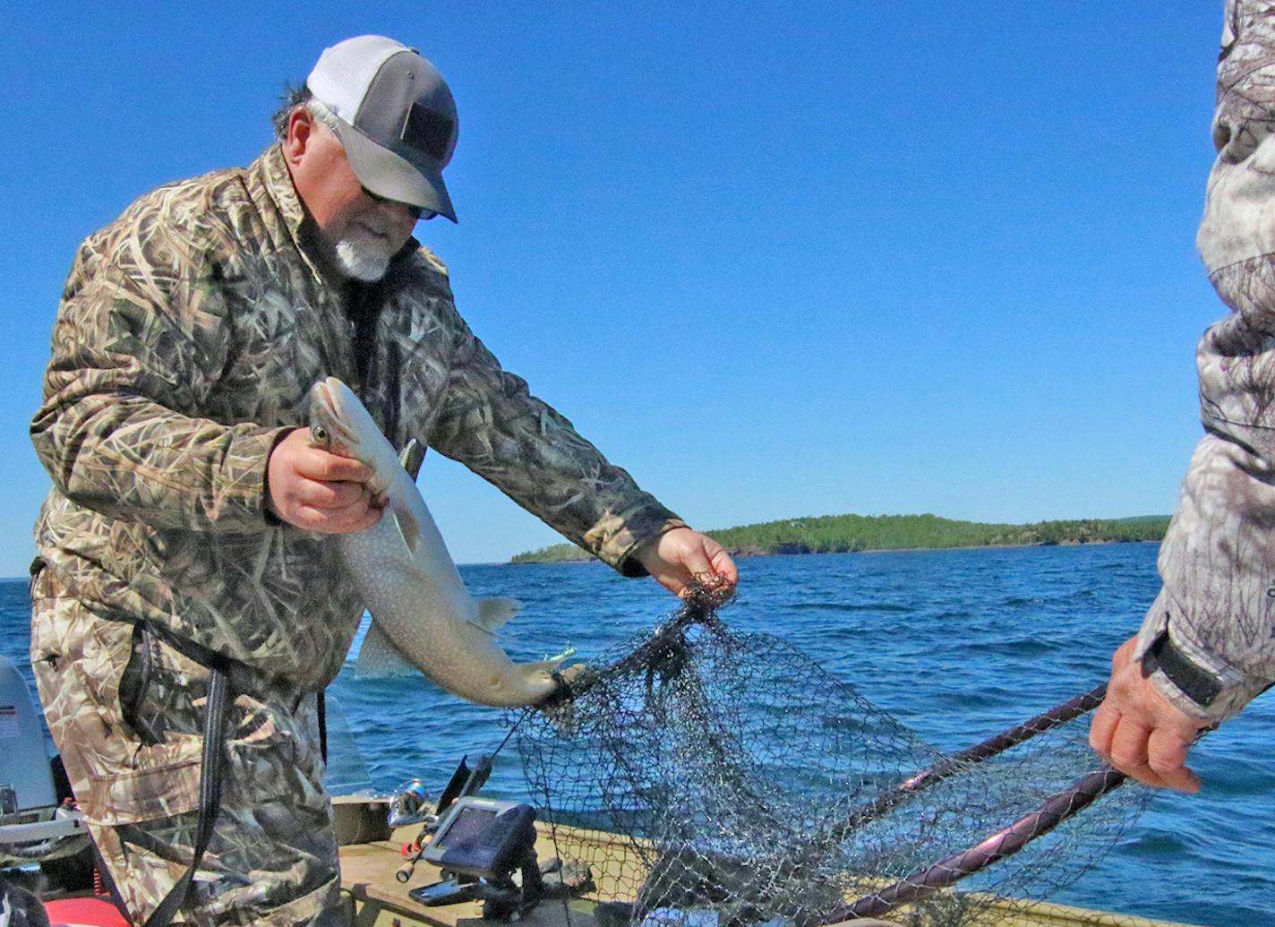 Loren Slette of Duluth removes a lake trout he caught in 165 feet of water on Lake Superior, north of the city. His fishing buddy, Bruce Sederberg, handled the net. The two friends frequently jig for the bottom-dwelling fish when Lake Superior gives them a window of calm water.