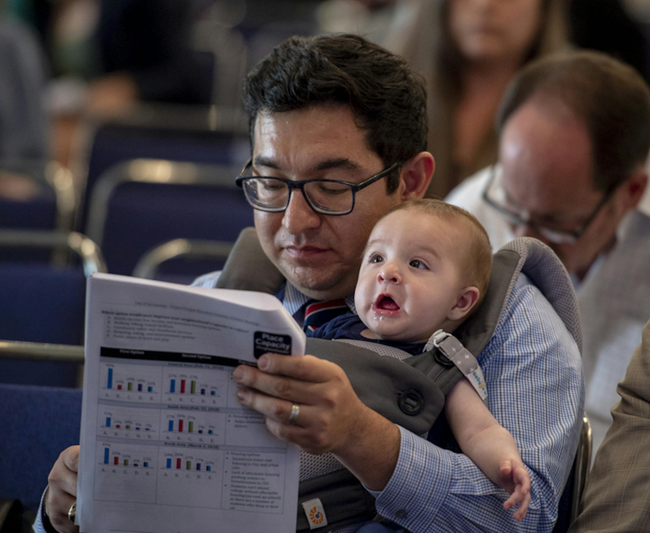 Sacramento councilman Eric Guerra, carries his son Javier as he reads through the agenda before addressing the Project Prosper Community Meeting at the Sacramento Convention Center on Thursday, April 26, 2018. ORG XMIT: B7312246621Z.1