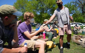 Zach Johnson, a program director with Southside Harm Reduction Services, passes out naloxone kits to community members as they gather for an overdose