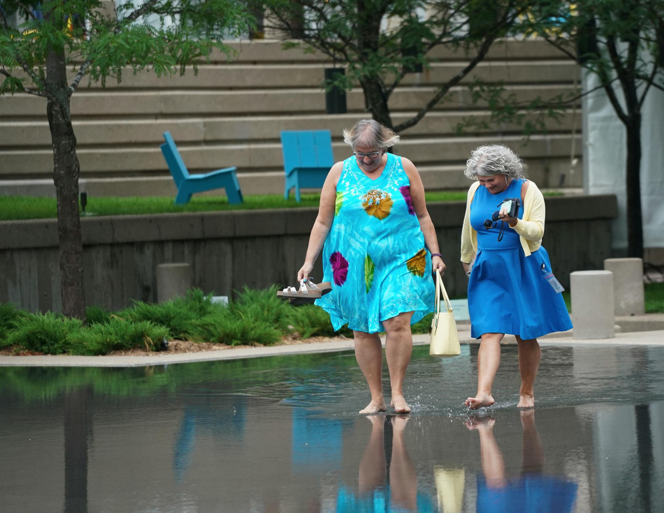 Minneapolis city council member Lisa Goodman and Tina Erazmus, left to tight were among the first to walk across the quarter-inch deep water of the Peavey Plaza reflecting pool during a re-opening of the space after renovations July 18, 2019 in Minneapolis.