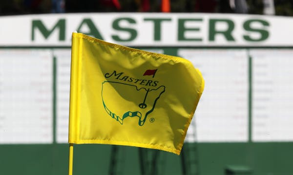 The Masters golf pin flag on the ninth green is seen with the scoreboard along the first fairway in the background at Augusta National Golf Club on Su