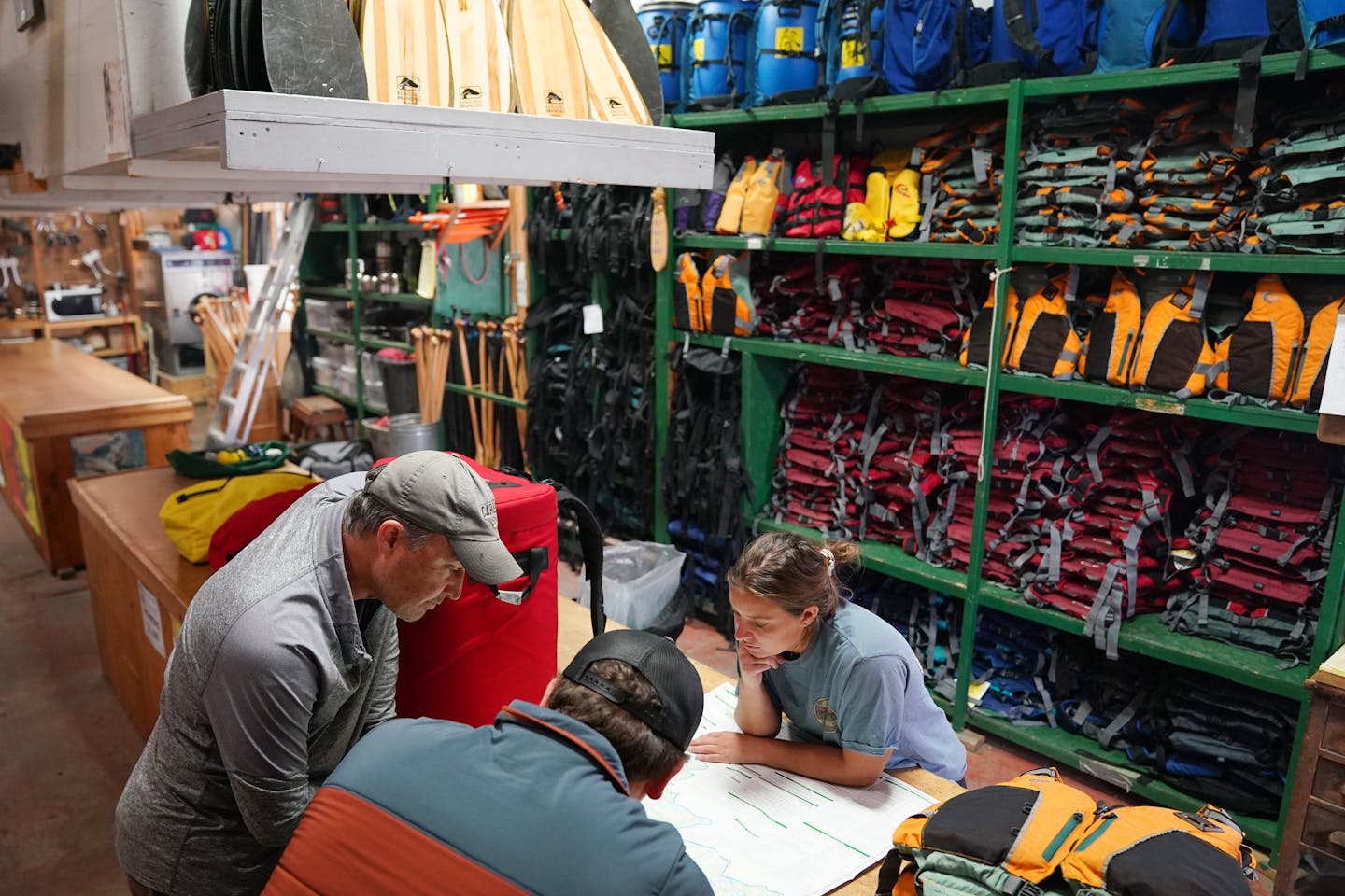 Assistant manager Jakob Willschau, bottom, and Emily Roose, right, of Piragis North Woods Co., an outfitter in Ely, showed Adam Battani, left, where to go canoeing Thursday in another part of the Superior National Forest. The Battanis had intended on a five-day trip in the Boundary Waters Canoe Area Wilderness.