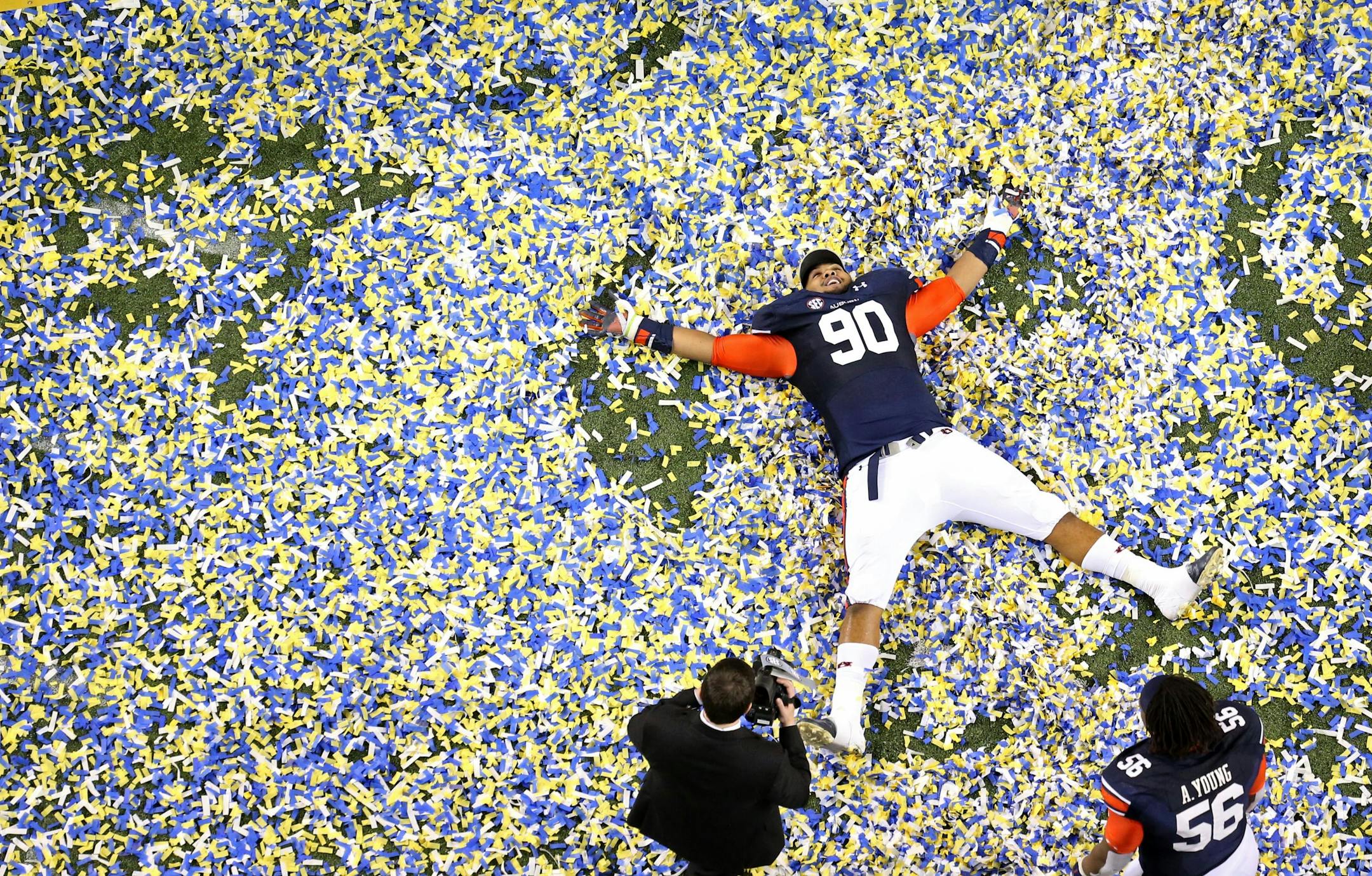 Auburn defensive tackle Gabe Wright (90) does snow angles in confetti after Auburn's 59-42 win over Missouri in the SEC Championship Saturday night in Atlanta, Ga., Dec. 7, 2013. (AP Photo/Atlanta Journal-Constitution, Jason Getz)