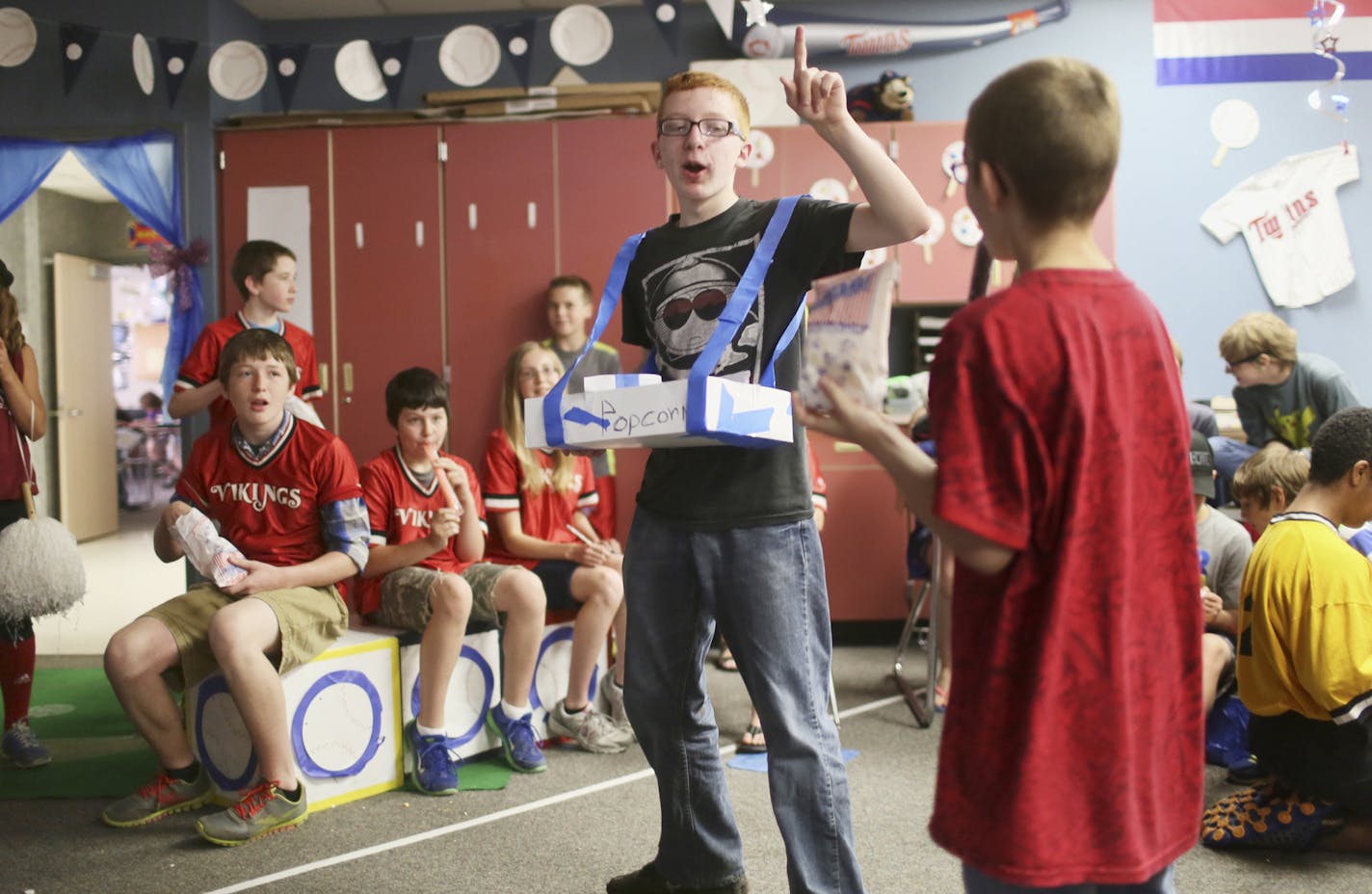 In teacher Marcia Schindler's eighth grade advanced math class, eighth graders are paired with fifth grade math buddies during a game of virtual baseball at North Branch Middle School Thursday, May 5, 2014, in North Branch, MN. In the game students play a baseball game based on statistics and probability and on things in their world like baseball. Here, during a break in game action eighth grader Tyler Wolvers hands out popcorn. The fifty eight minute classes of a four-day school week allow teac