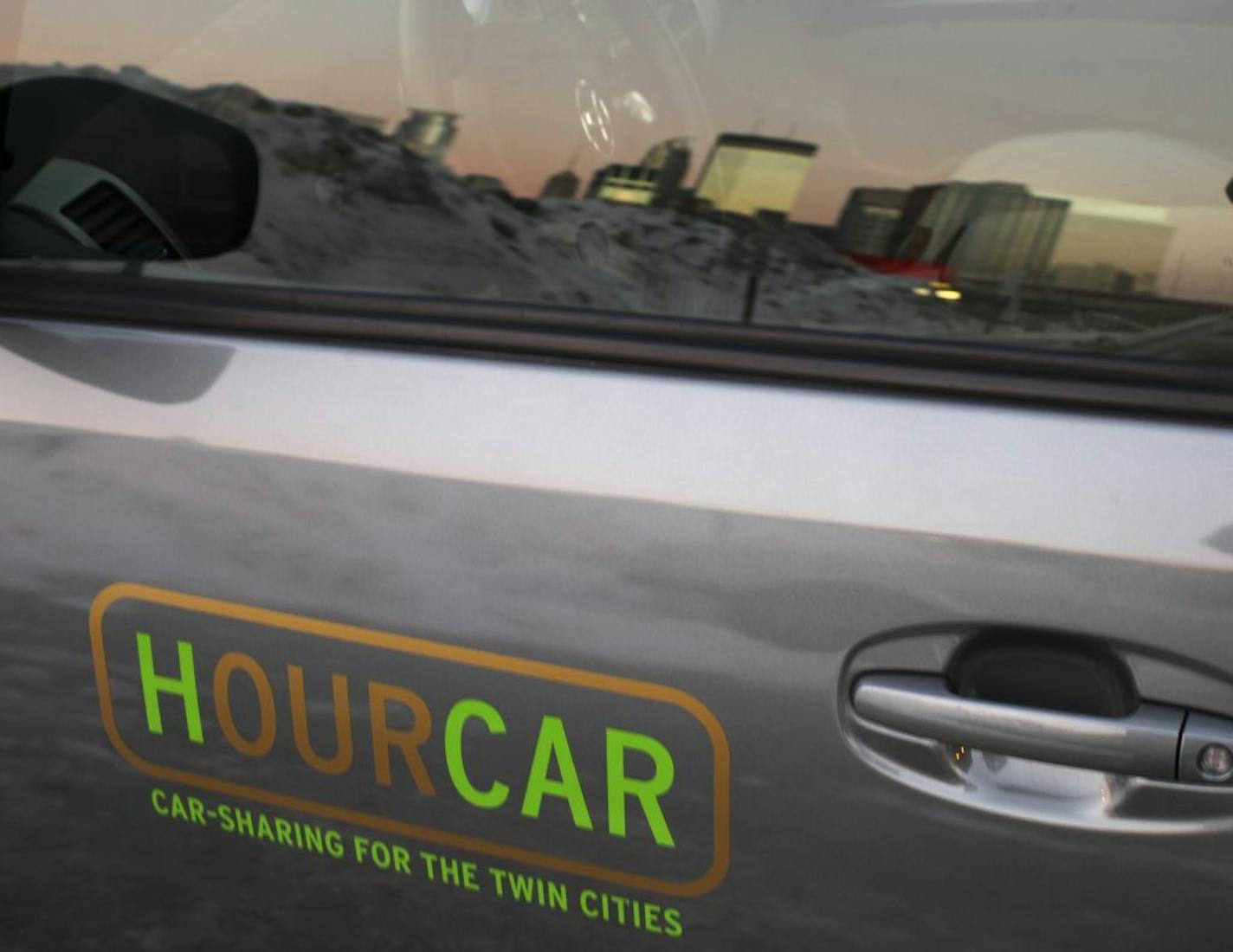 The HOURCAR that Tome Altenhoff had reserved time on was parked in a lot off Nicollet Ave., near downtown, reflected in the car's window.