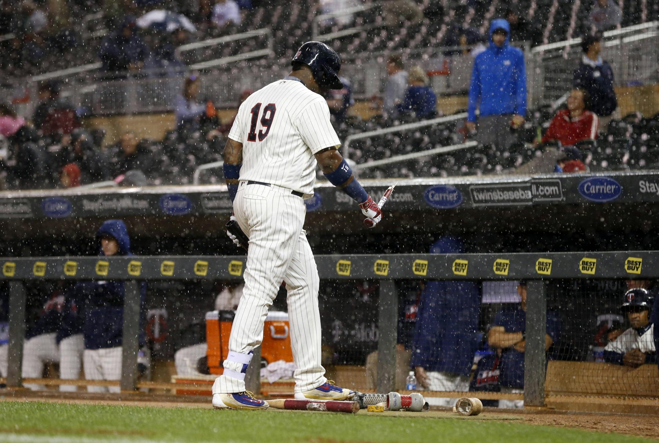 Minnesota Twins' Kennys Vargas heads to the dugout as the rain comes, after breaking his bat on striking out on a pitch from Detroit Tigers pitcher Buck Farmer in the third inning of a baseball game Wednesday, Sept. 21, 2016, in Minneapolis.