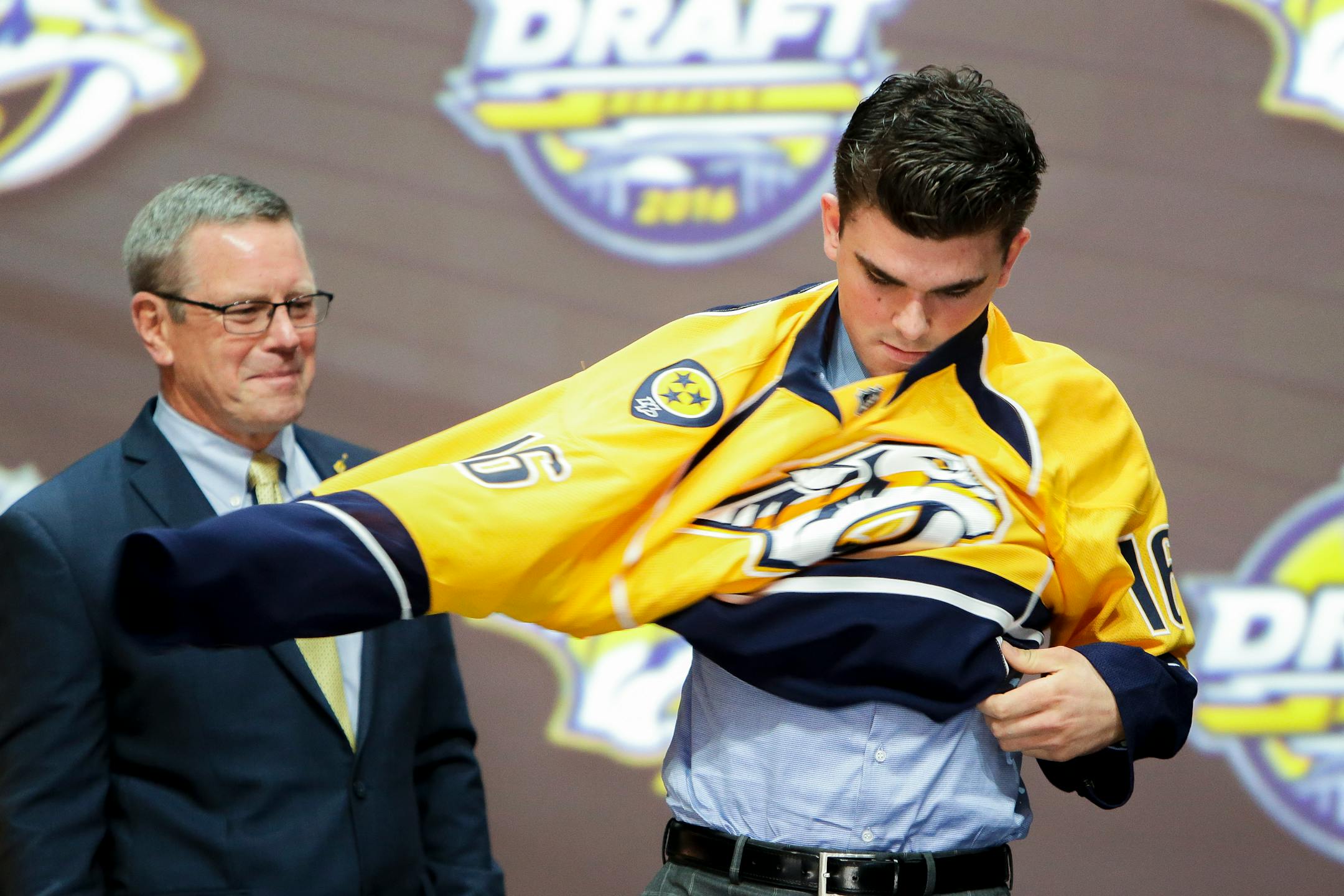 June 24, 2016: Dante Fabbro dons the Predators jersey after he was selected as the 17th pick in the first round of the 2016 NHL Entry Draft at First Niagara Center in Buffalo, NY. at left is Predators assistant general manager Paul Fenton. (Photo by John Crouch/Icon Sportswire.) (Icon Sportswire via AP Images)