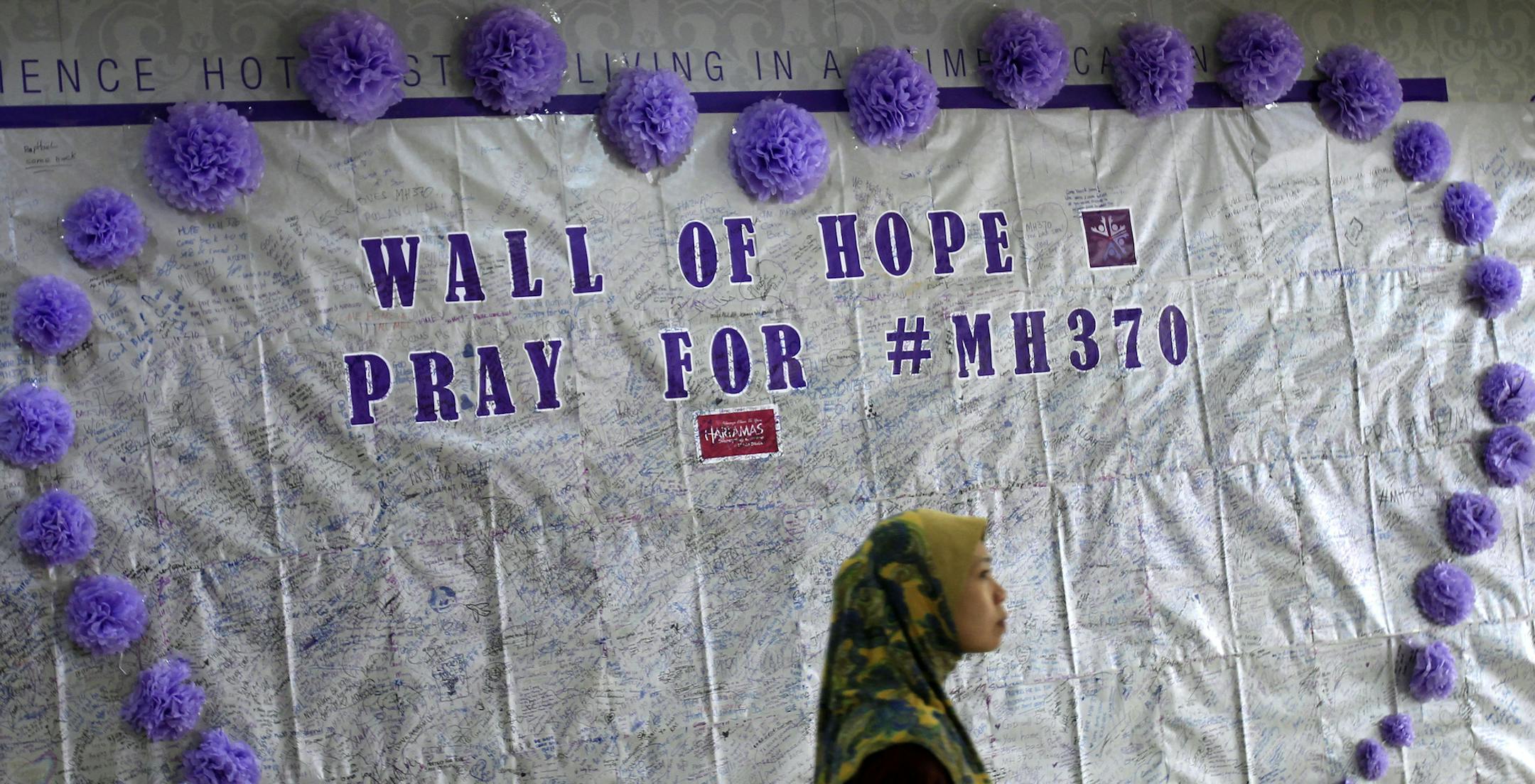 FILE - In this March 23, 2014 photo, a woman walks past a message board for passengers aboard a missing Malaysia Airlines plane, at a shopping mall in Kuala Lumpur, Malaysia. With no answers yet in the disappearance of Malaysia Airlines Flight 370, investigators have said they’re considering many options: hijacking, sabotage, terrorism or catastrophic equipment failure. Nobody knows if the pilots are heroes who tried to save a crippled airliner or if one collaborated with hijackers or was