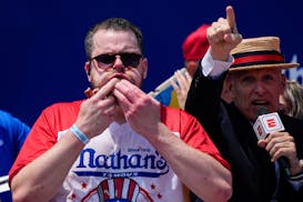Patrick Bertoletti stuffs hot dogs into his mouth during the men's division in Nathan's Famous Fourth of July hot dog eating contest, Thursday, July 4