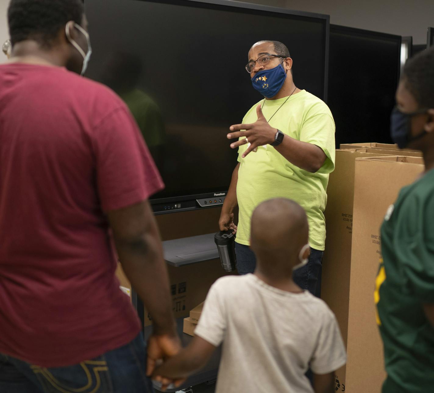 Friendship Academy of the Arts Executive Director B. Charvez Russell, right, explained to returning parent Ile Lakte and sons David and William how technology is enhancing distance learning.