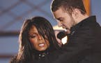 Justin Timberlake reaches across Janet Jackson during their performancs just before he pulled off the covering to her right breast, which was partiall