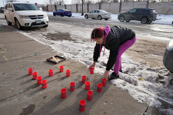 Tonya Medvec set candles along Hudson Road in St. Paul on Tuesday near where her nephew, Howard Johnson, died.